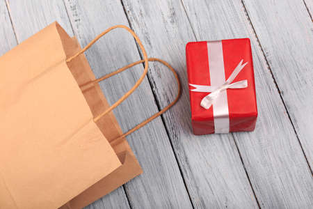 Paper package on a gray wooden background with a red gift.の写真素材