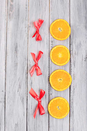 Orange slices and red bows on a gray wooden table.の写真素材