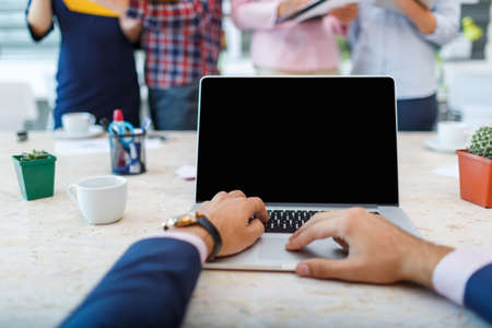 Laptop from the first person on the background of a group of office workersの写真素材