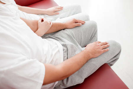Legs of a man and a girl in white pants hang from a red sofa on top
