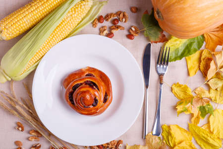 Fallen leaves of autumn concept of autumn on the background of cloth tablecloth with an empty sheet of paper with autumn vegetables with a plate with a roll.の写真素材