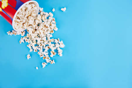 Popcorn is scattered in the upper left corner on a blue background. Empty space for text. Close-up. View from above.の写真素材