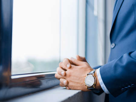 Close-up of a businessman in a stylish formal wear on a blurred window background. Macro of rich man in a suit with a watch. Copy space.の写真素材