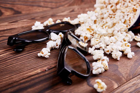 Bowl with scattered popcorn and 3D glasses on a wooden backgroundの写真素材