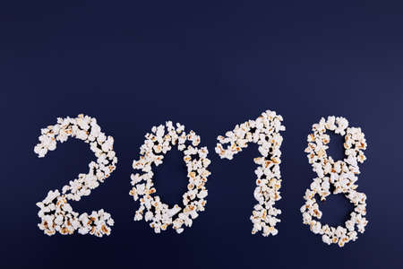 2018 is scattered over popcorn on a blue background. Empty space for text. Close-up. View from above.の写真素材
