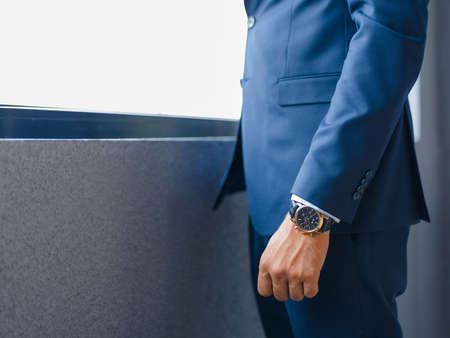 Close-up of a businessman in a stylish formal wear on a blurred window background. Macro of rich man in a suit with a watch. Copy space.の写真素材
