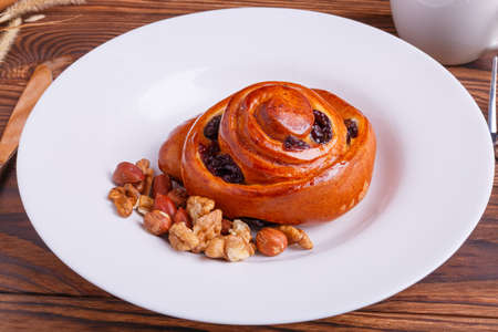 Composition of autumn vegetables on a brown wooden background with a plate of brioche and in the middle of a pumpkin, corn, peanuts, leavesの写真素材