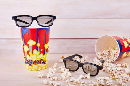 Bowl with scattered popcorn and 3D glasses on a wooden backgroundの写真素材
