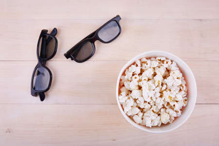 Bowl with popcorn and 3D glasses on a wooden background top viewの写真素材
