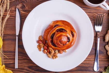 Composition of autumn vegetables on a brown wooden background with a plate of brioche and a cup of coffee in the middle of a pumpkin, corn, peanuts, leavesの写真素材