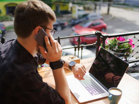 Portrait of successful young businessman speaking by phone while working in cafe outdoorsの写真素材