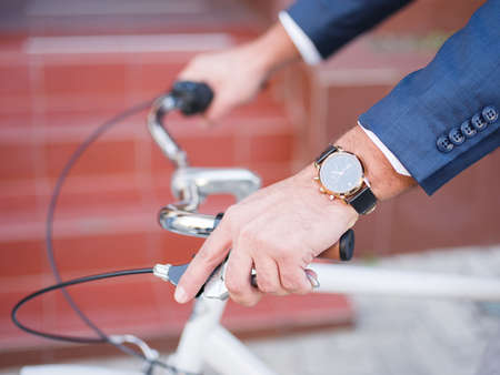 Businessman rides on his white bicycle on the street close-up clockの写真素材