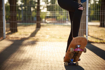 The legs of a skateboarder girl in sneakers do a trick on a skateboard in a park in the fresh air. Close-up.の写真素材