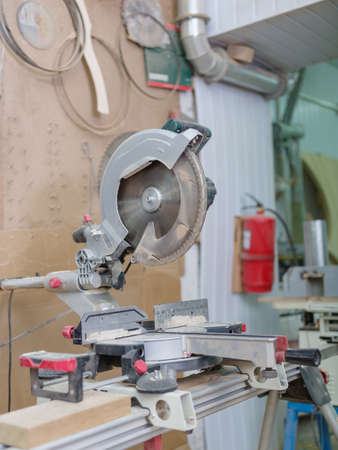 Gray machine circular saw with protection so as not to harm yourself, against the background of the fire extinguisherの写真素材