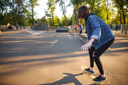 A young girl is riding a skateboard. Skateboarding. Outdoors, lifestyle. Close-up. A view from the side. In full growth.の写真素材