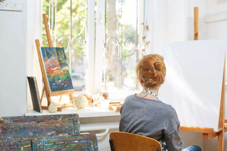 Beautiful smiling girl artist posing on camera. Window on the background. Art concept.の写真素材