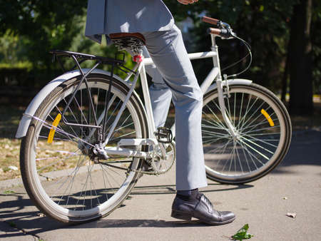 A guy in a gray suit is sitting on his bike and is not going anywhere on a sunny day