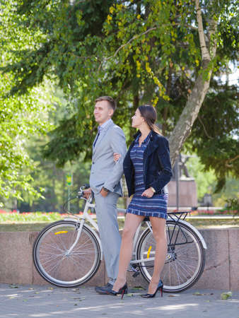 A guy with a bicycle and a girl is walking along the streetの写真素材