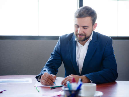 A young businessman signs documents at his desk.の写真素材