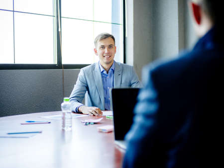 Young man in suit, at desk in office. Close-up .の写真素材