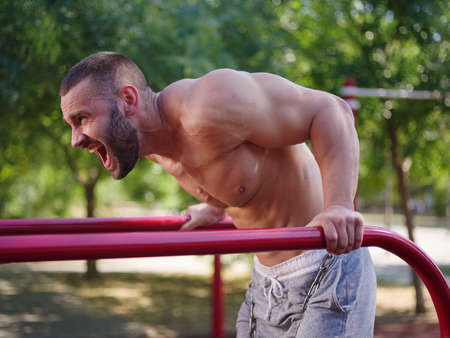 Athletic, sexy handsome man bodybuilder working out on a blurred background. Building muscles...