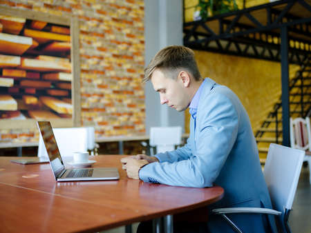 Young man sitting in front of his laptop with a cup of coffee.の写真素材