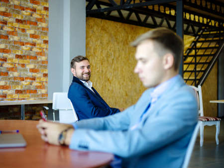 Young man sitting in front of his laptop with a phone in his hands.の写真素材