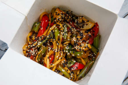 Noodles with vegetables in a white box for export on a wooden gray table. Close-up. View from above.の写真素材