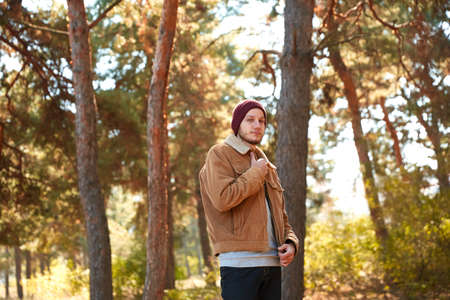 A handsome young man walking in the autumn forest
