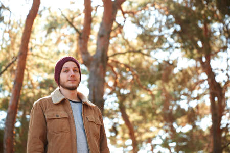 A handsome young man walking in the autumn forest
