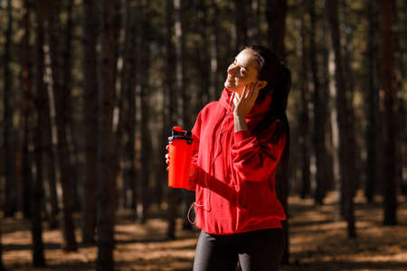 Young sporty woman in red sweatshirt. In the woods.