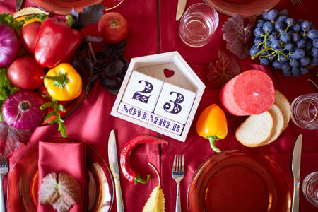 A beautiful festive table served with a red tablecloth. Different vegetables, glasses, plates,...
