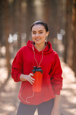 Young sporty woman in red sweatshirt. In the woods.