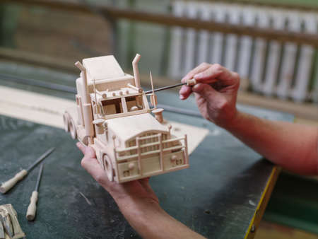 Wooden car close-up with hands of the masterの写真素材