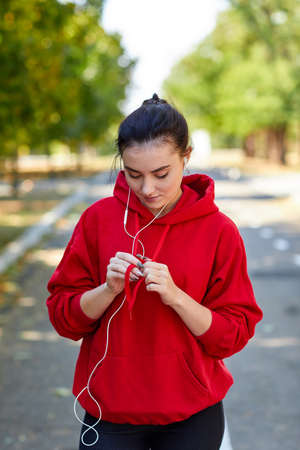 The girl on a run corrects the laces from the hood on her uniform