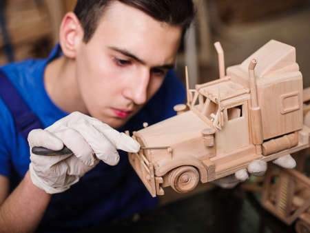 Wooden car close-up with hands of the masterの写真素材