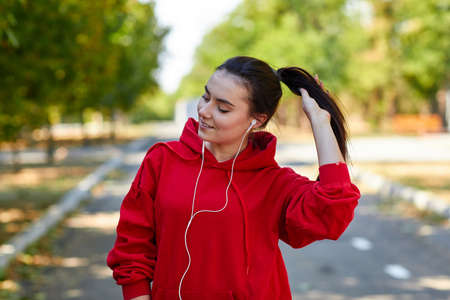 A girl jogs listening to music and straightening her hair