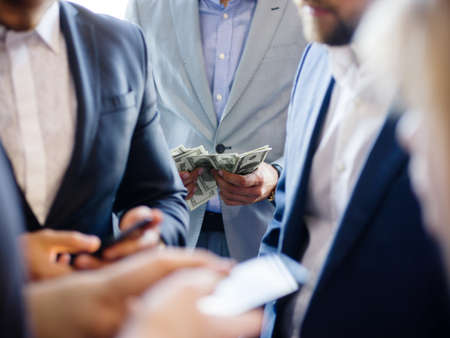 Businessman with a phone close-up on other businessmen in good expensive suits with phones and moneyの写真素材