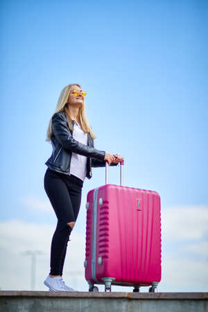 Girl with a pink suitcase on a background of a beautiful blue skyの写真素材