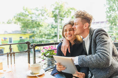 Romantic couple with a tablet at the cafe on a blurred background. Romance concept. Copy space.の写真素材