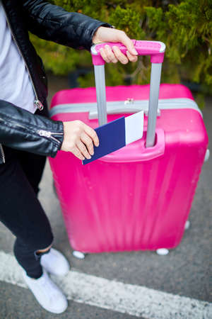 A girl with a pink suitcase stands on the street close upの写真素材