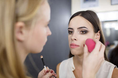 A make-up artist is applying makeup to a young girl.の写真素材