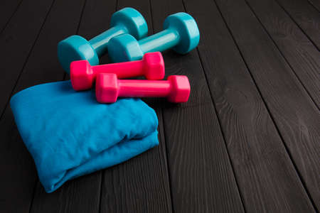 Dumbbells of blue and pink plastic on a brown wooden background.の写真素材