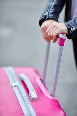 Pink suitcase close-up with hand girl on handleの写真素材