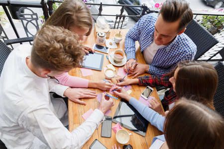 Close-up students writing on a table background. People working with papers and devices. Project work concept.の写真素材