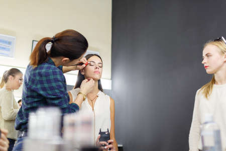 A make-up artist is applying makeup to a young girl.