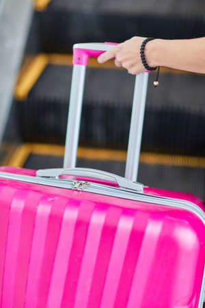 Pink suitcase with a young girl on the escalatorの写真素材