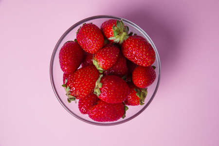 Strawberries in a bowl on a pink table backgroundの写真素材