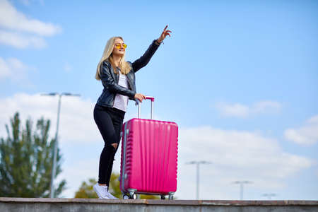 Girl with a pink suitcase on a background of a beautiful blue skyの写真素材