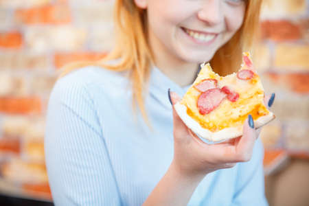 Smiling office lady, at lunchtime and eating pizza. Festive atmosphere.